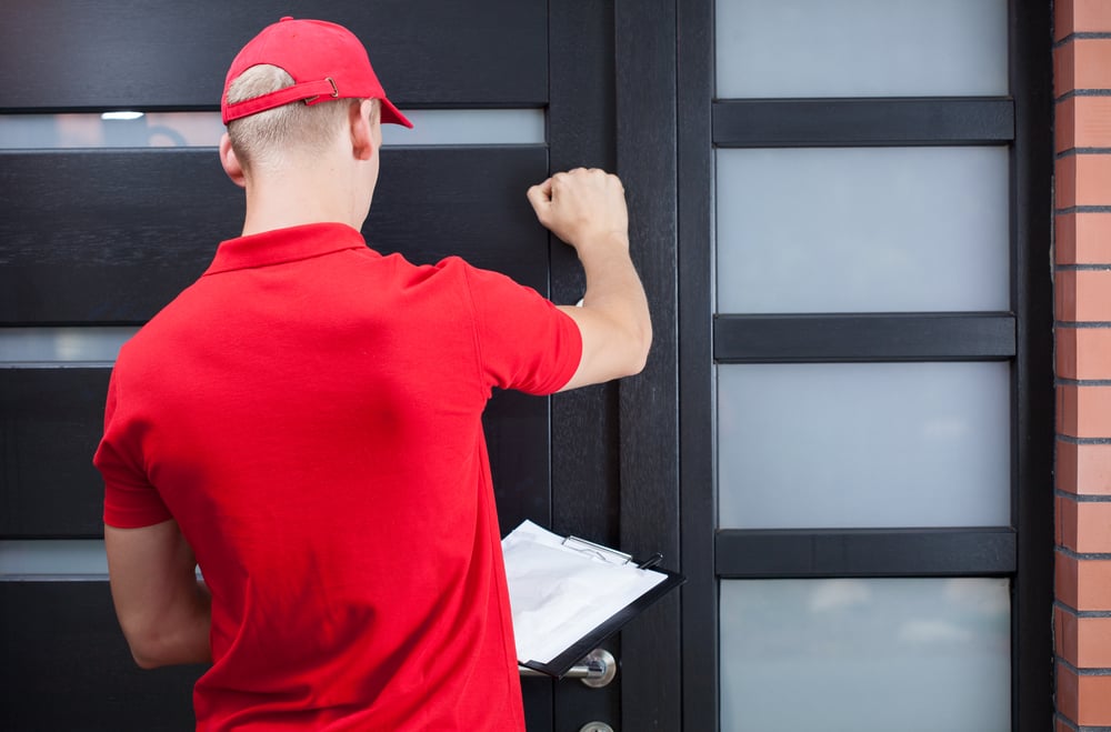 Back view of a delivery man knocking on the clients door-3