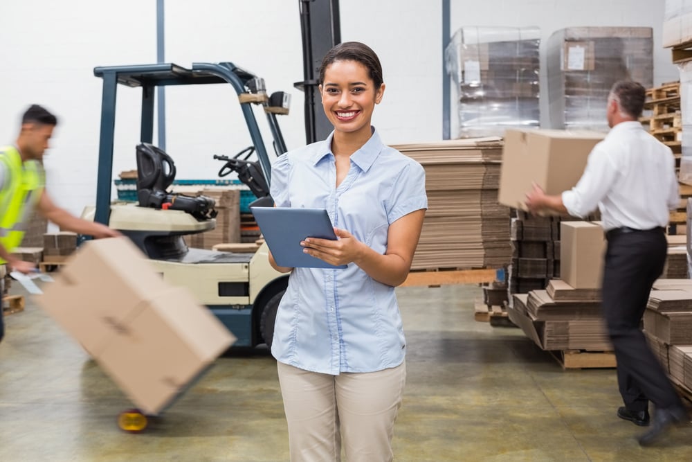 Smiling manager using digital tablet during busy period in a large warehouse-1